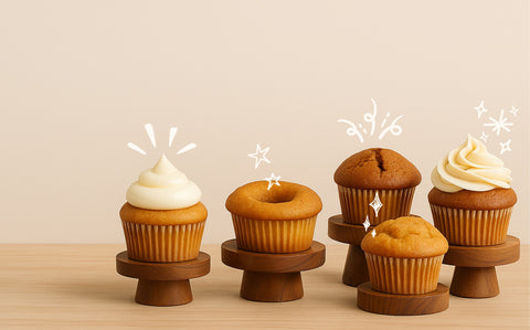 Five cupcakes on wooden stands against a beige background